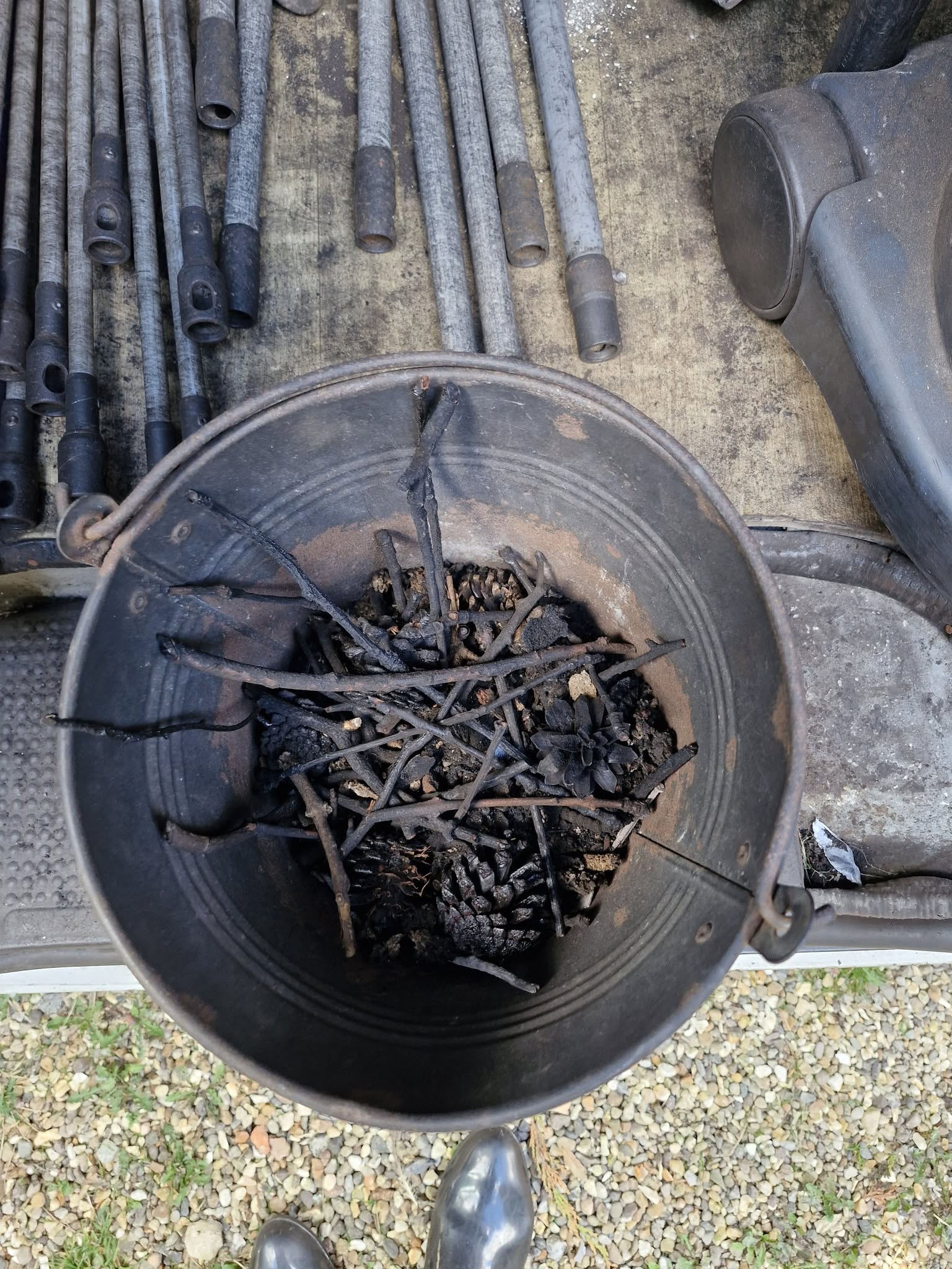 A metal bucket full of pine cones and twigs taken out of a stove