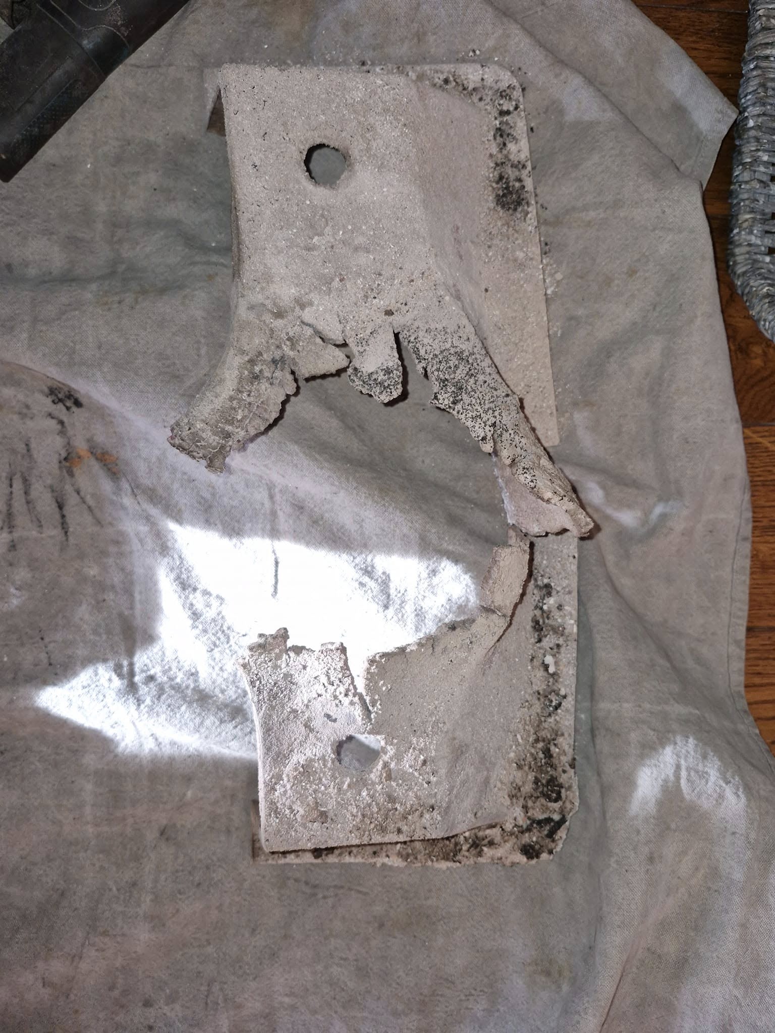 A soot-caked stove baffle plate on a dust sheet