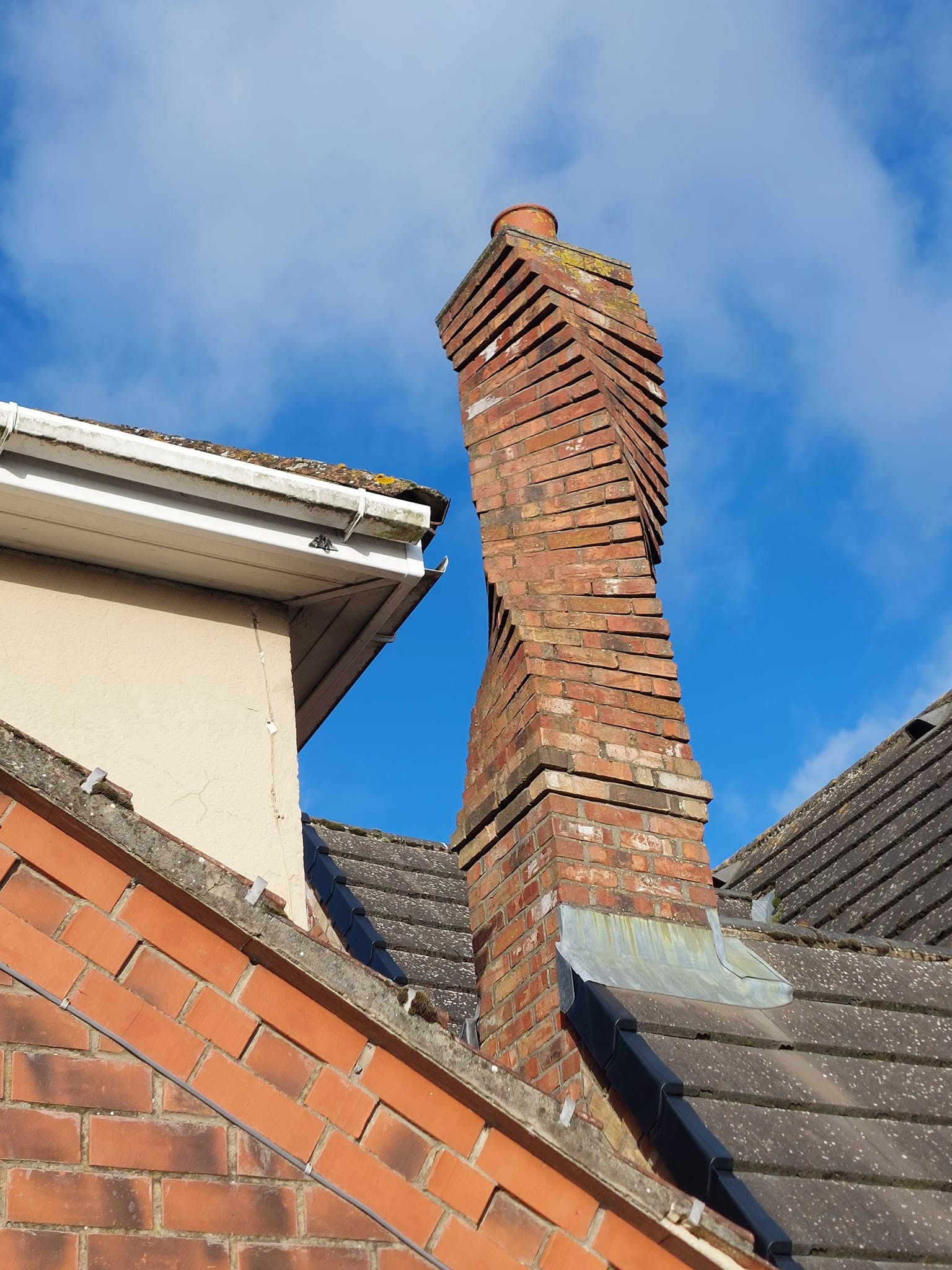 A tall brick chimney stack on a house against a blue sky