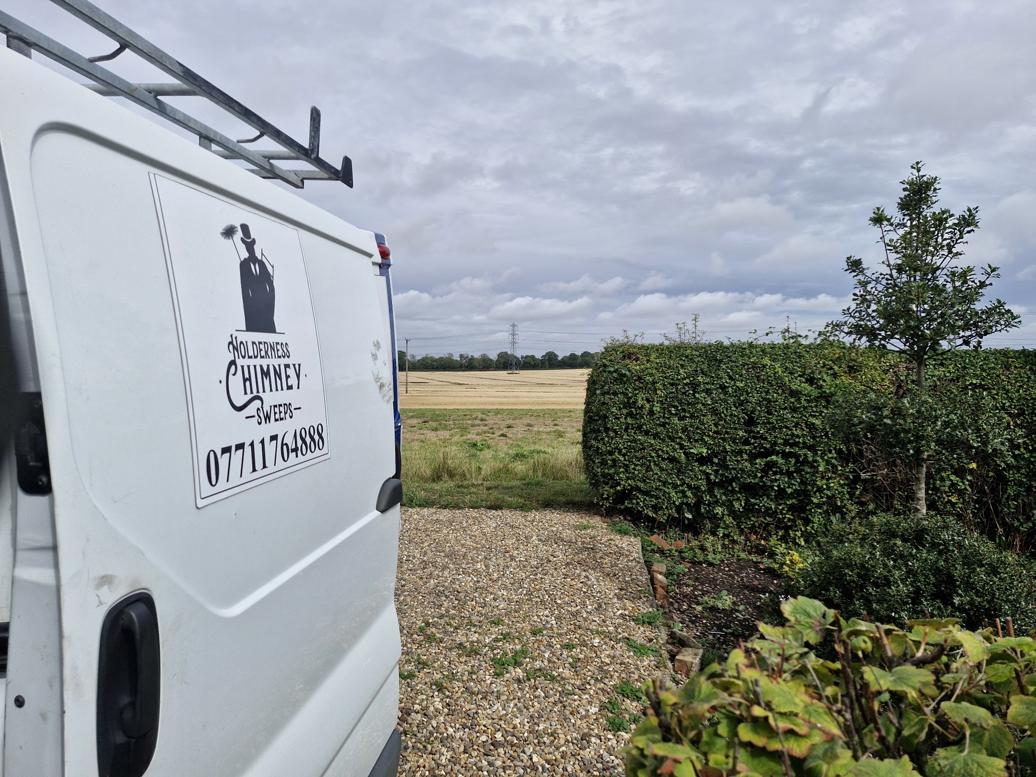The white Holderness Chimney Sweeps van with the top-hat sweep logo on the back door