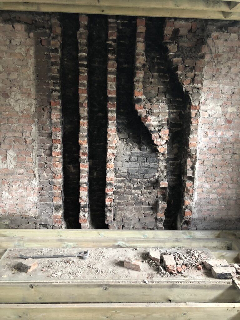 A brick chimney breast opened up to show soot-blackened flue channels
