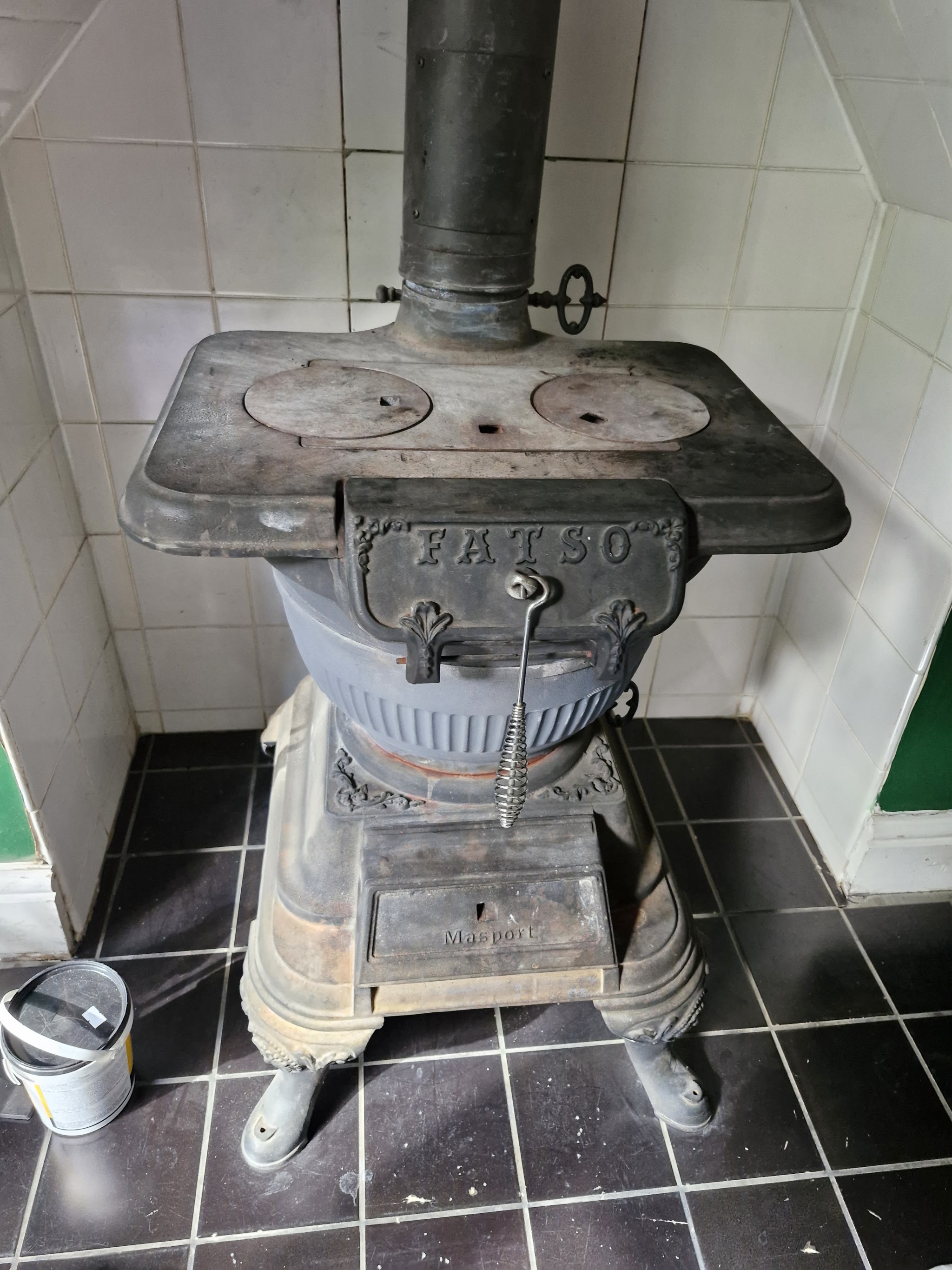An antique cast-iron Fatso pot-belly stove on a tiled floor